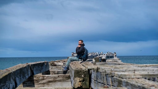 A man sits on a pier with birds